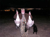 Picture of hunter holding up two large geese.