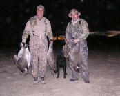 Picture of two hunters their geese and their dog.